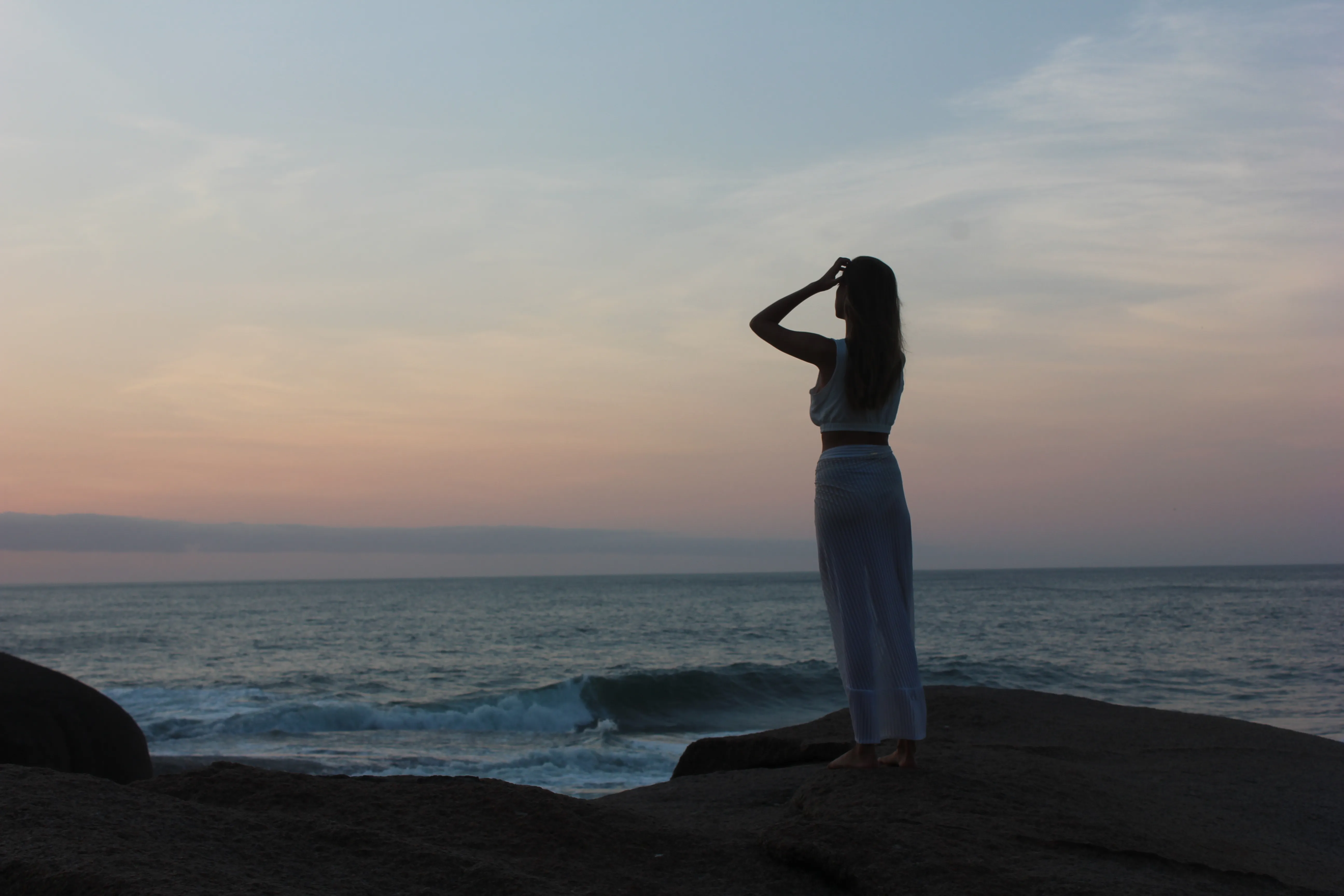 Silhouette gazing at the ocean at sunset