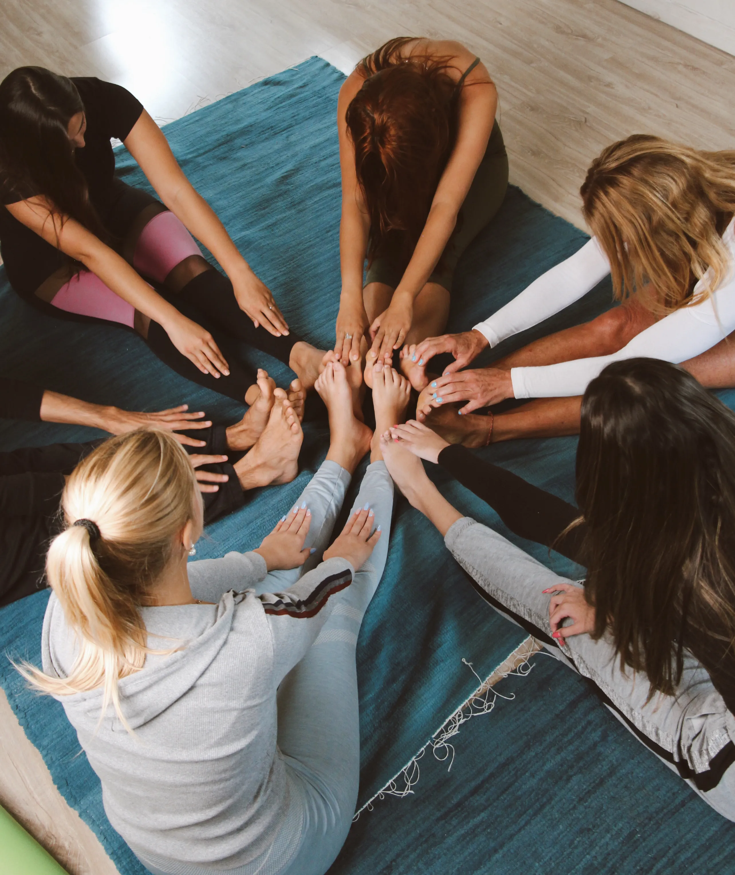 Students in a circle touching hands and feet in community